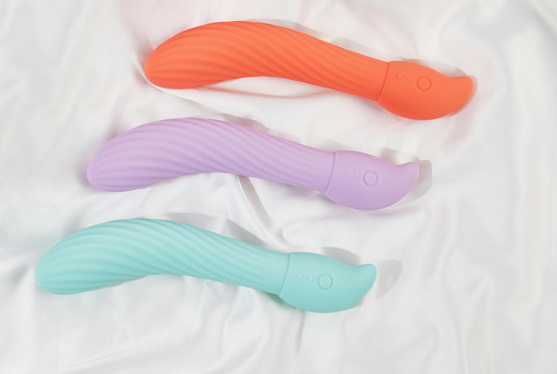 Woman holding blue and pink silicone vibrators with contemplative expression