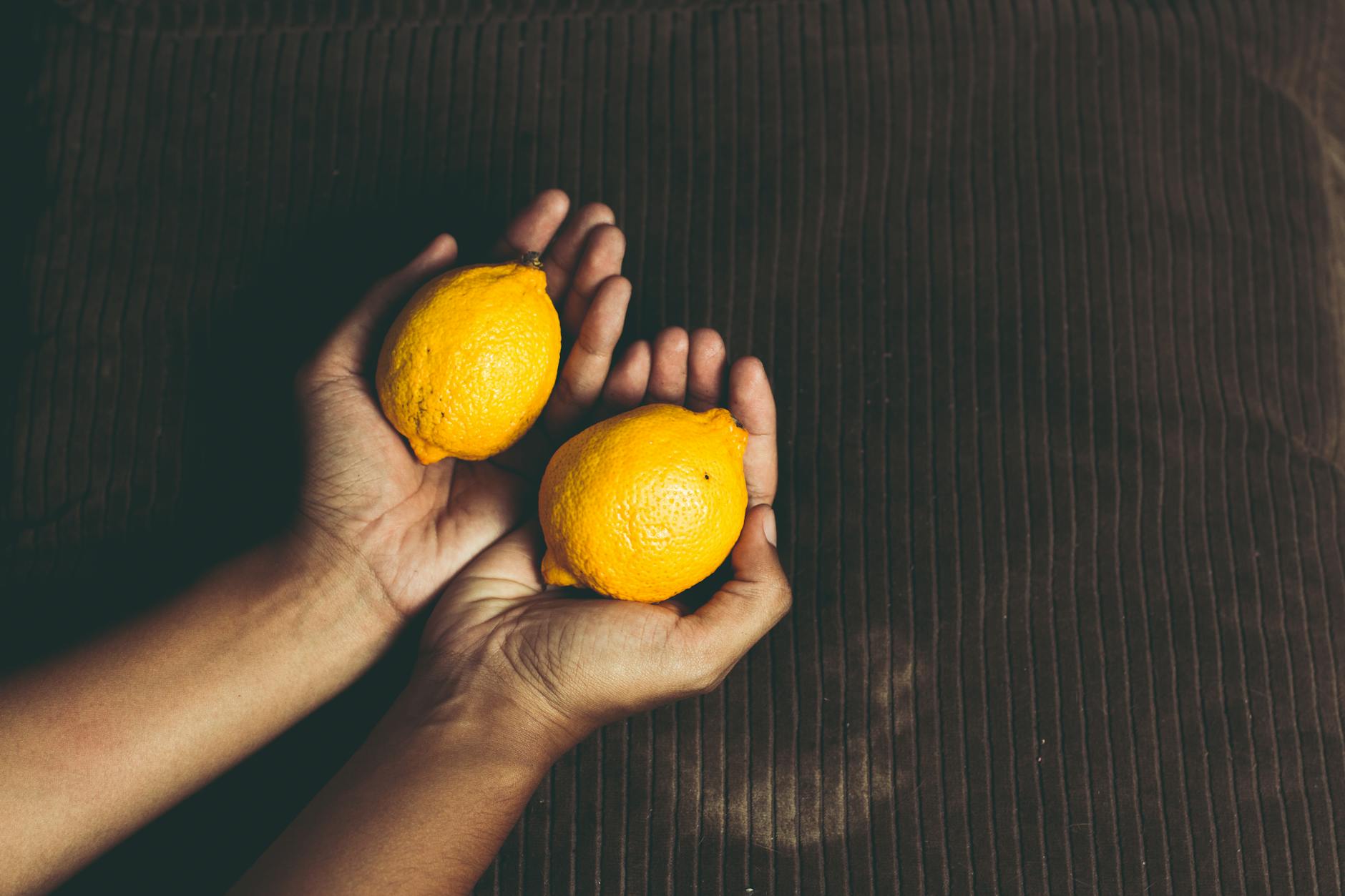 Hands holding fresh lemons, symbolizing natural pleasure and renewal