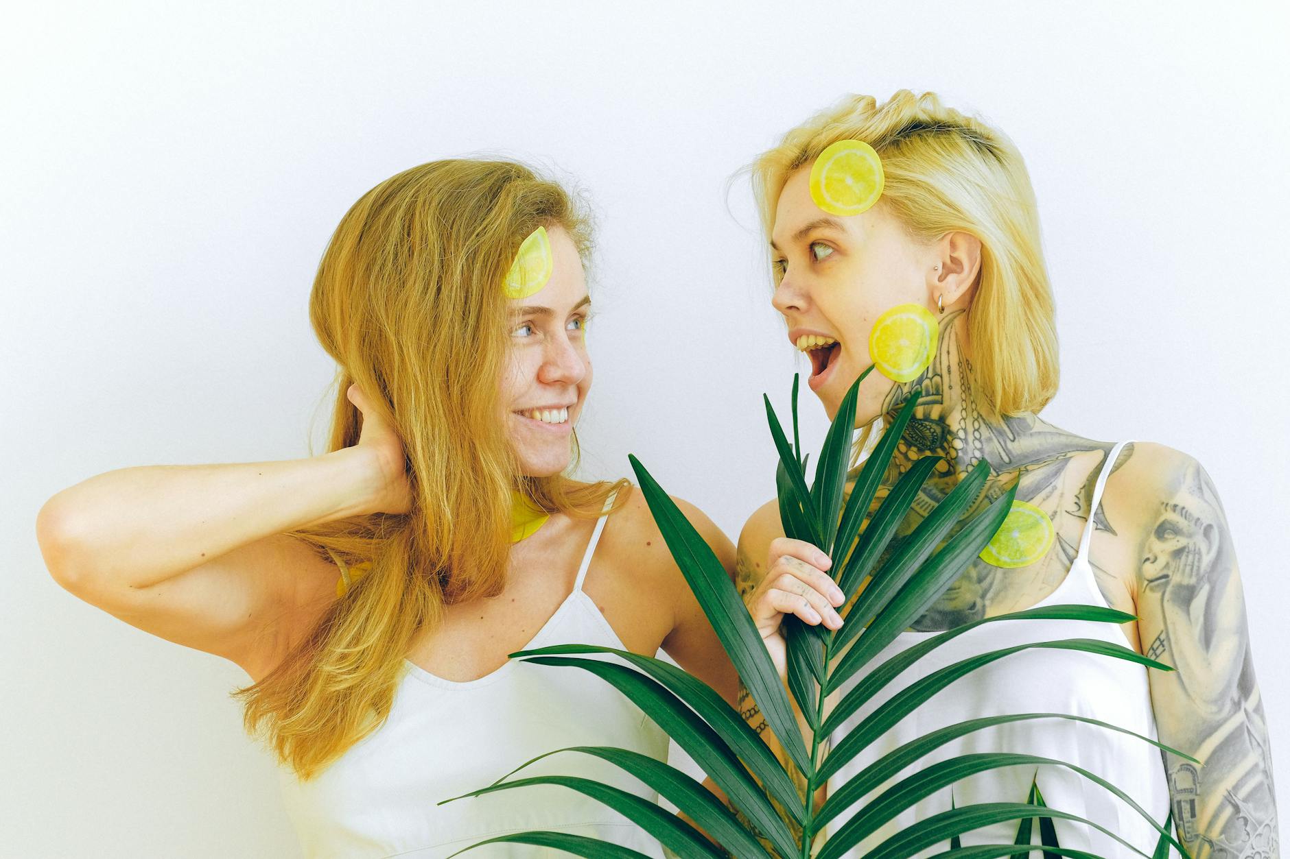 Two women smiling with tropical fruit, expressing joy and fun