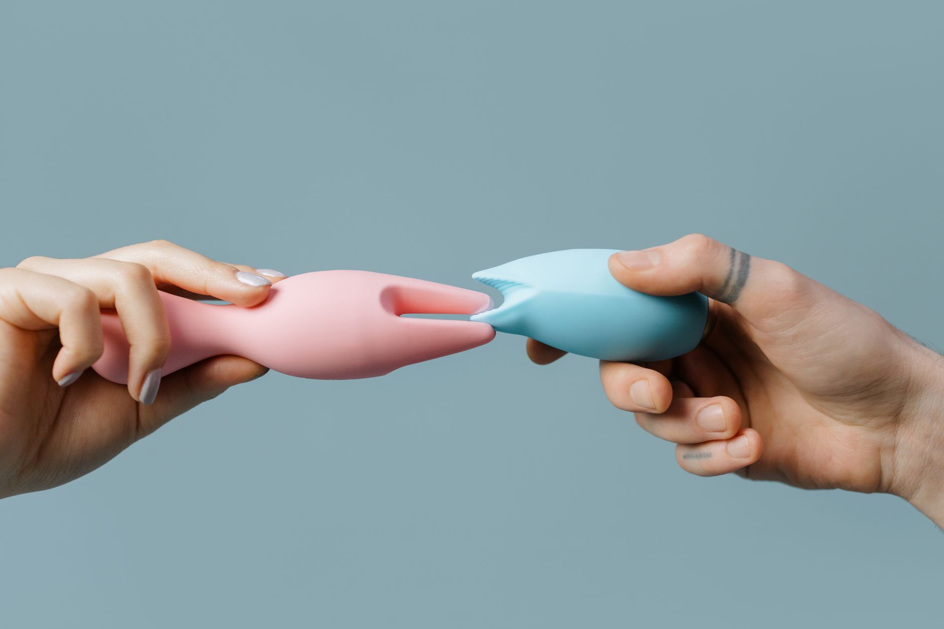 Mãos segurando brinquedos de silicone em cores pastel