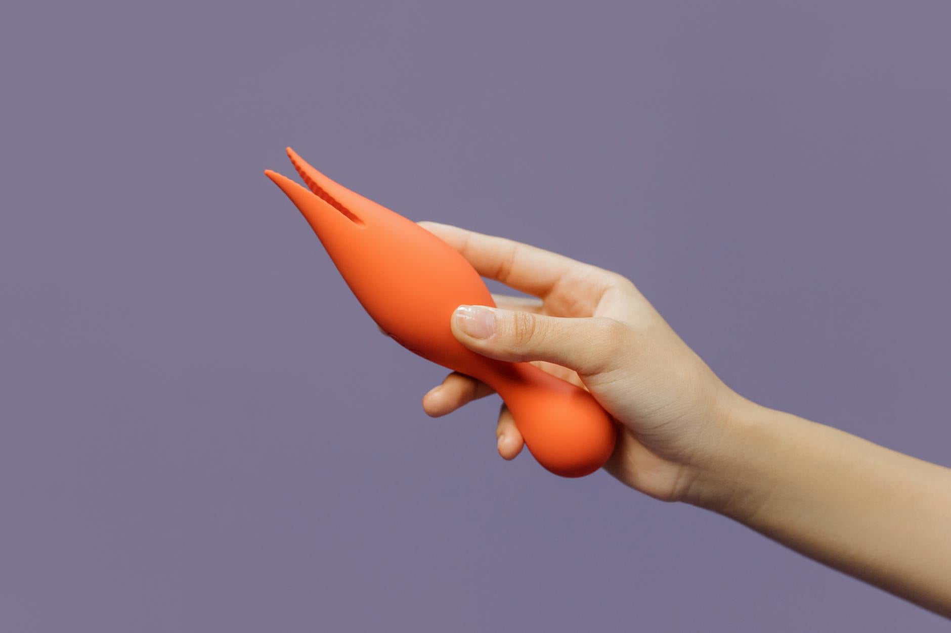 Hand holding a lemon clitoral vibrator against a soft purple background, symbolizing gentle healing and sensuality