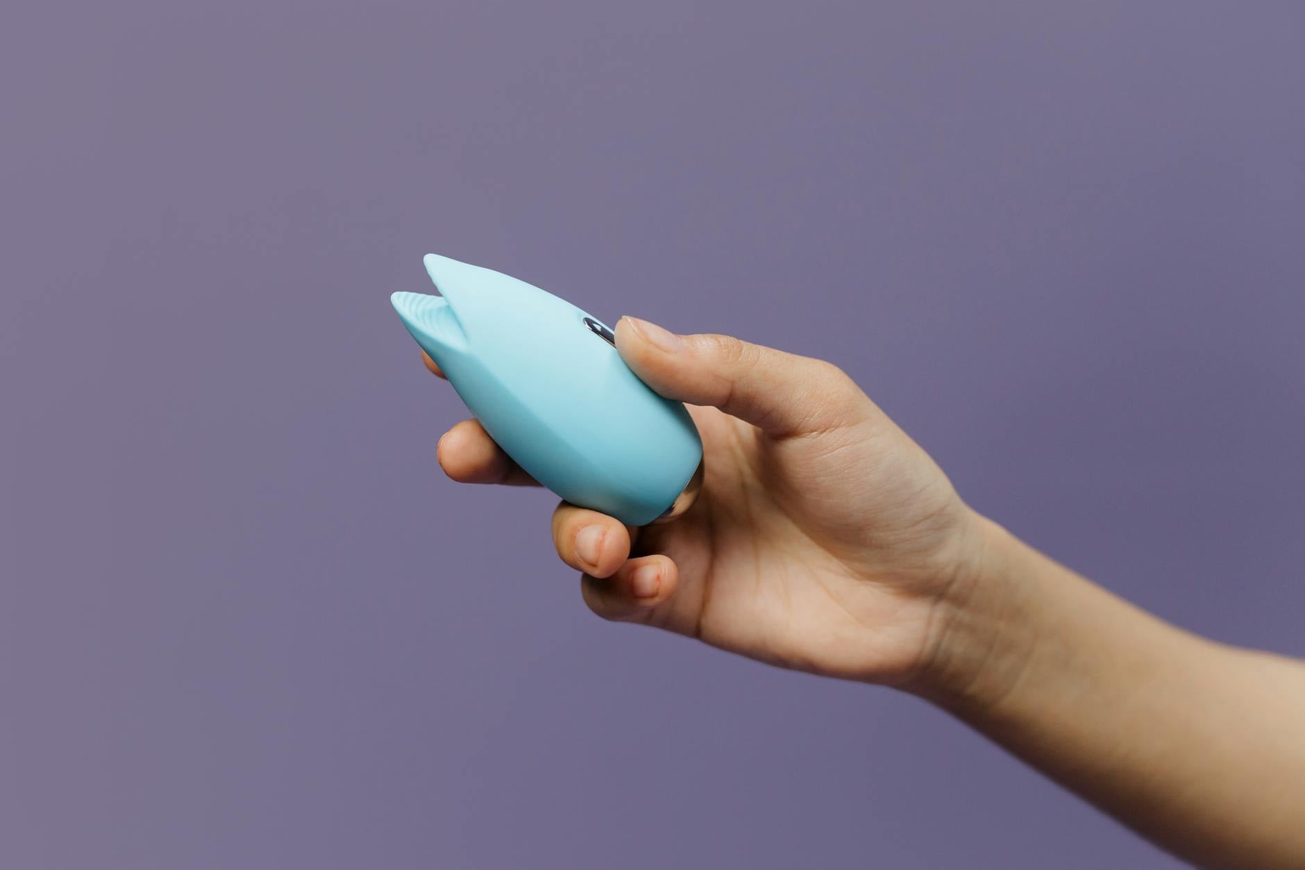 A teal vibrator resting on soft white silk, representing intimacy and self-pleasure.