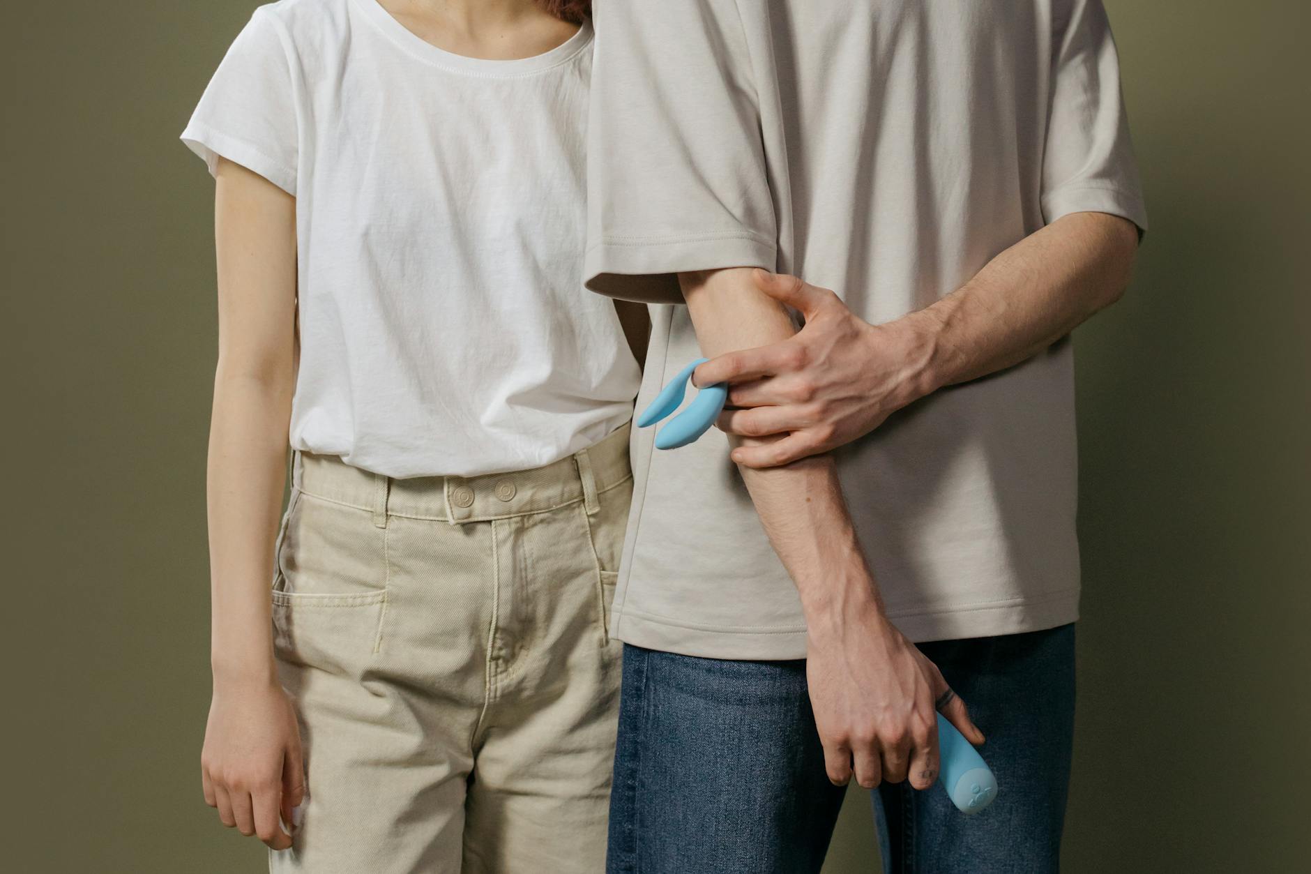 A couple holding a blue vibrator together, representing communication and shared intimacy.